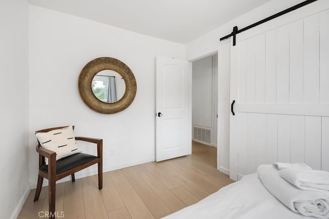 bedroom featuring a barn door and light hardwood / wood-style flooring