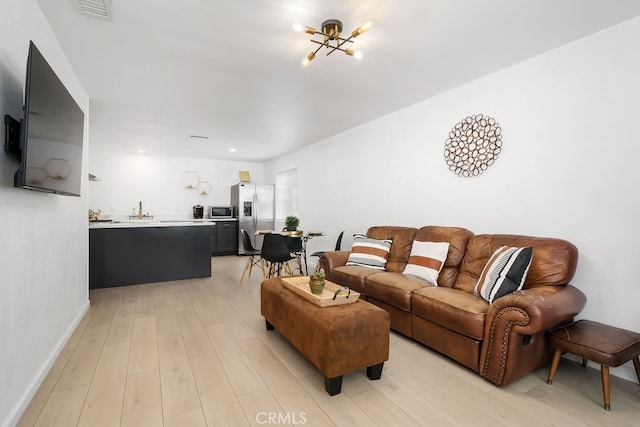 living room featuring a chandelier, light hardwood / wood-style floors, and sink