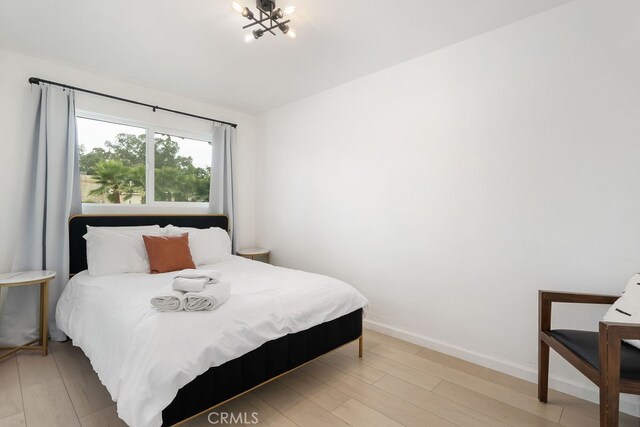 bedroom featuring an inviting chandelier and light hardwood / wood-style floors