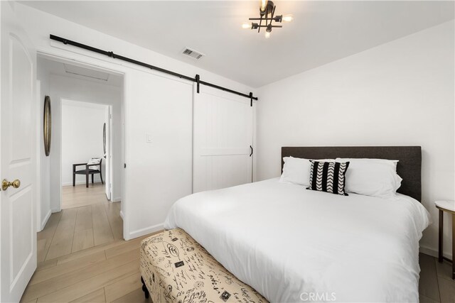 bedroom with hardwood / wood-style floors, a notable chandelier, and a barn door