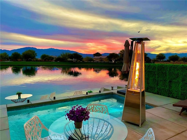 pool at dusk with a water and mountain view