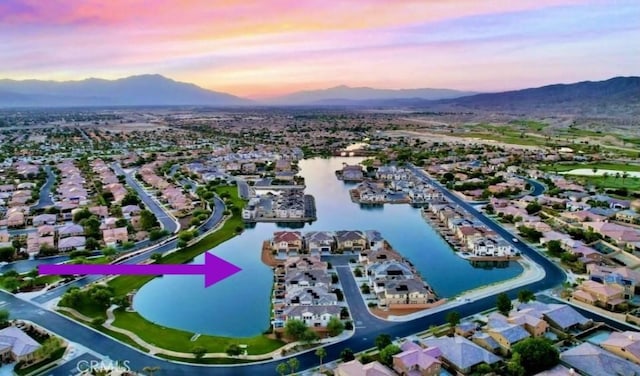 aerial view at dusk featuring a water and mountain view