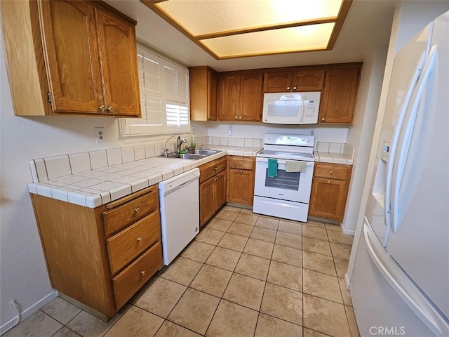 kitchen featuring tile countertops, sink, light tile patterned floors, and white appliances