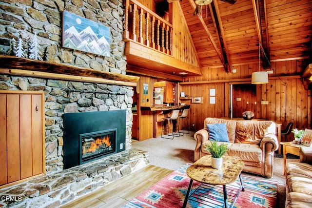 carpeted living room with a fireplace, beam ceiling, wood walls, high vaulted ceiling, and wood ceiling