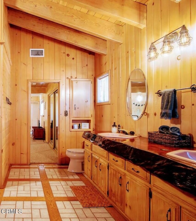 bathroom featuring vaulted ceiling with beams, wood walls, vanity, and toilet