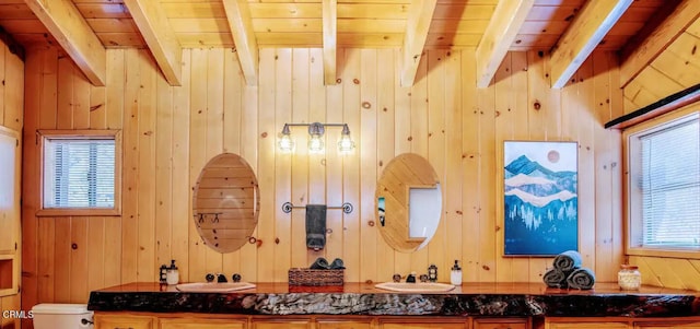 interior space with beam ceiling, wooden walls, and vanity