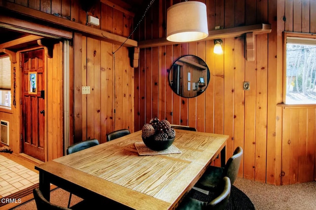 carpeted dining area with wooden walls