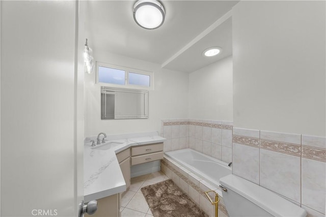 bathroom with tiled bath, toilet, vanity, and tile patterned flooring