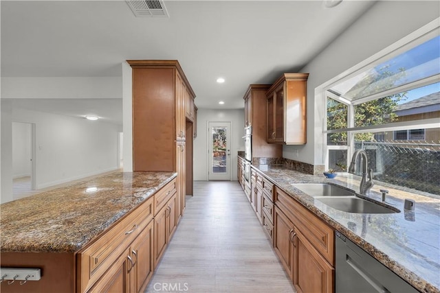 kitchen featuring sink, stainless steel dishwasher, dark stone counters, and light hardwood / wood-style floors