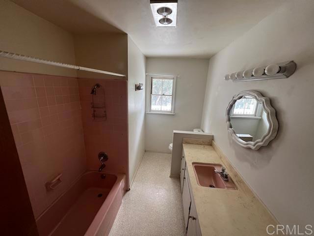 full bathroom featuring tiled shower / bath combo, vanity, and toilet