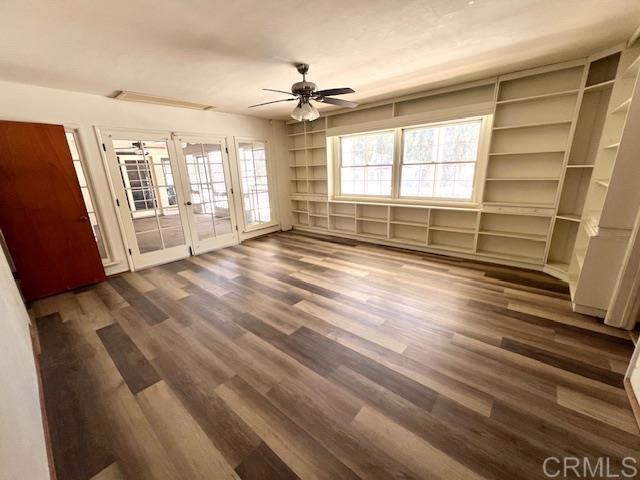 unfurnished living room with dark wood-type flooring, ceiling fan, and french doors