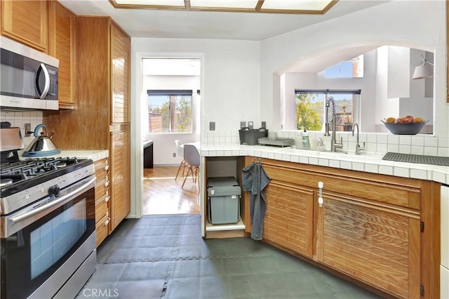 kitchen featuring tile countertops, plenty of natural light, appliances with stainless steel finishes, and tasteful backsplash