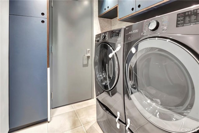 laundry area with cabinets, independent washer and dryer, and light tile patterned flooring