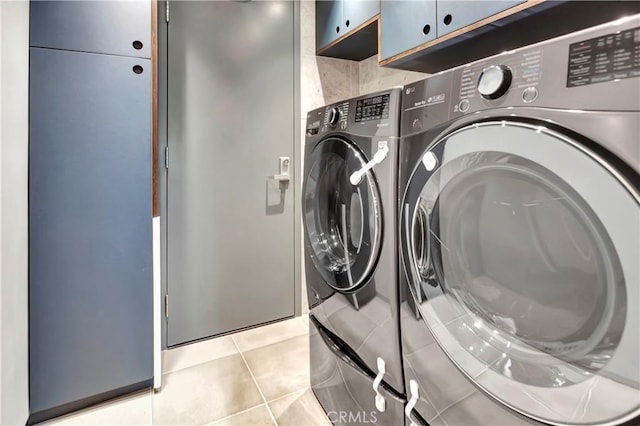 laundry room featuring washer and dryer, light tile patterned flooring, and cabinet space