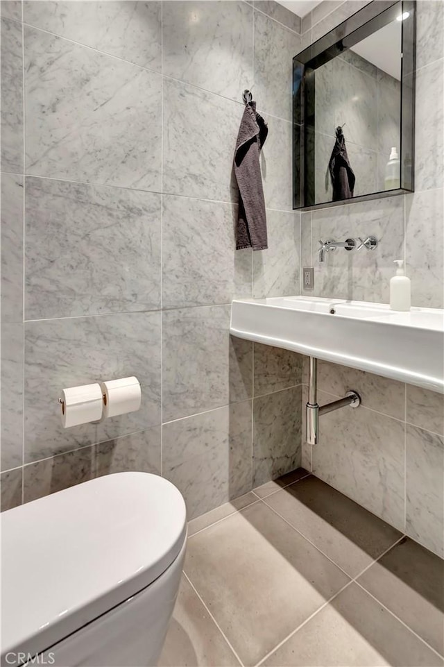 bathroom with tile patterned floors, tile walls, and toilet