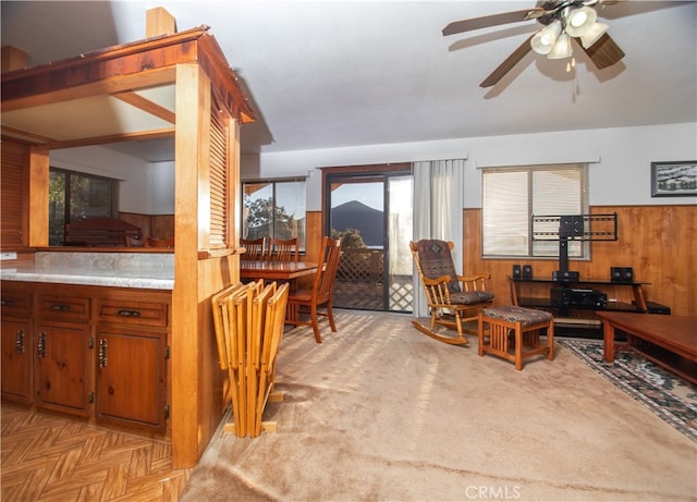 living room with ceiling fan and wood walls