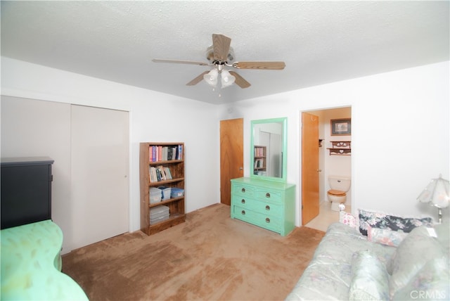 carpeted bedroom featuring a textured ceiling, ensuite bathroom, a closet, and ceiling fan