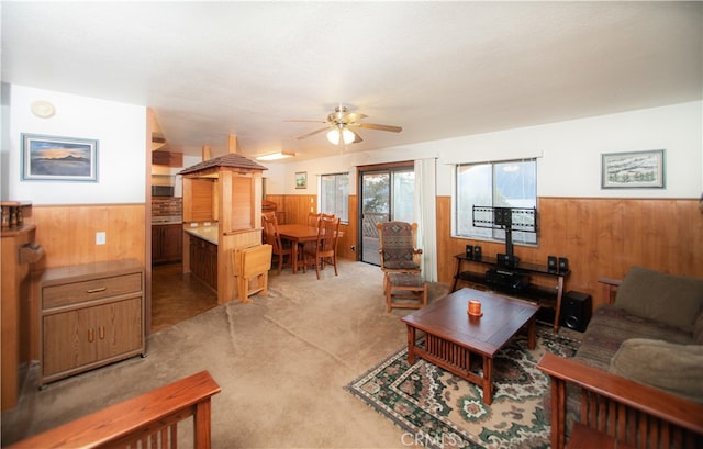 carpeted living room with a textured ceiling, wooden walls, and ceiling fan