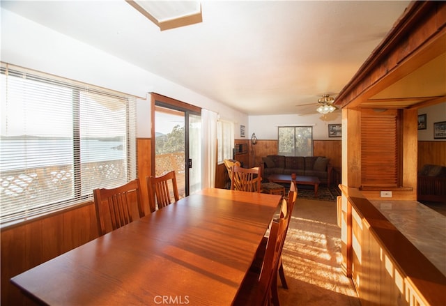 dining area with ceiling fan, wood walls, and carpet floors