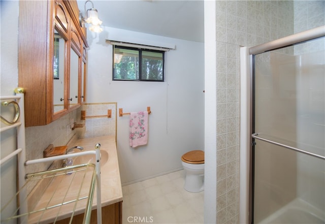 bathroom featuring toilet, vanity, and a shower with door