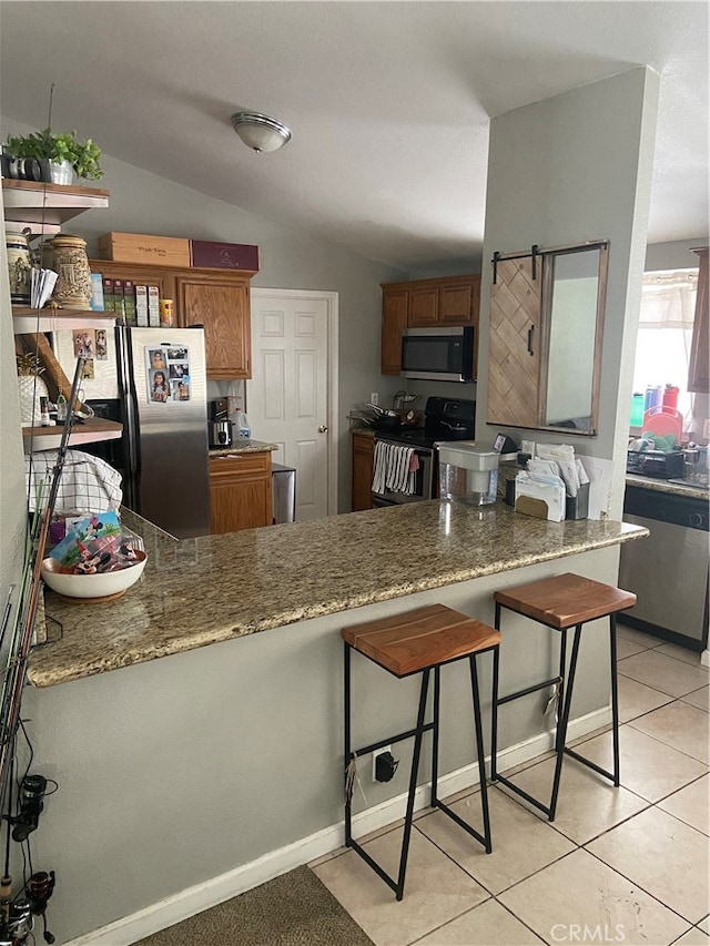 kitchen featuring a breakfast bar, stainless steel appliances, light tile floors, dark stone countertops, and lofted ceiling