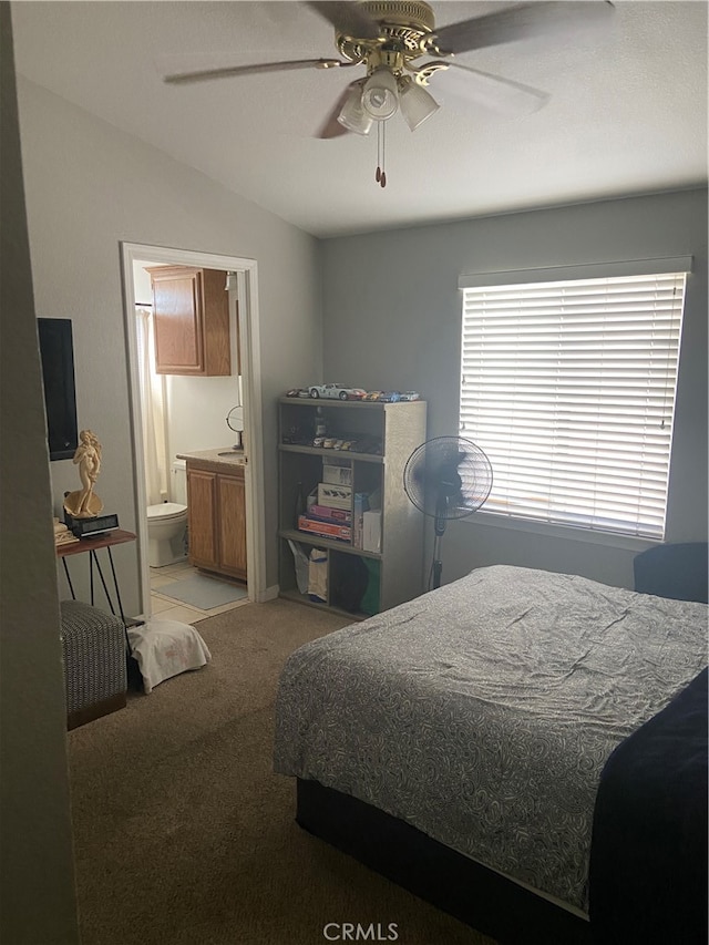 bedroom with vaulted ceiling, ceiling fan, light carpet, and connected bathroom