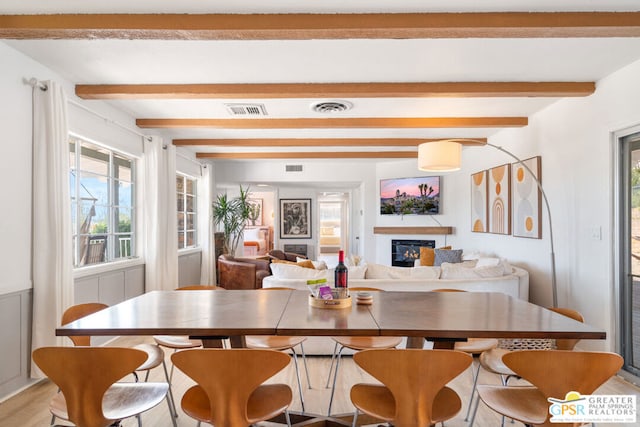 dining space featuring beamed ceiling and light hardwood / wood-style flooring