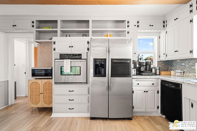 kitchen with appliances with stainless steel finishes, backsplash, light wood-type flooring, and white cabinetry