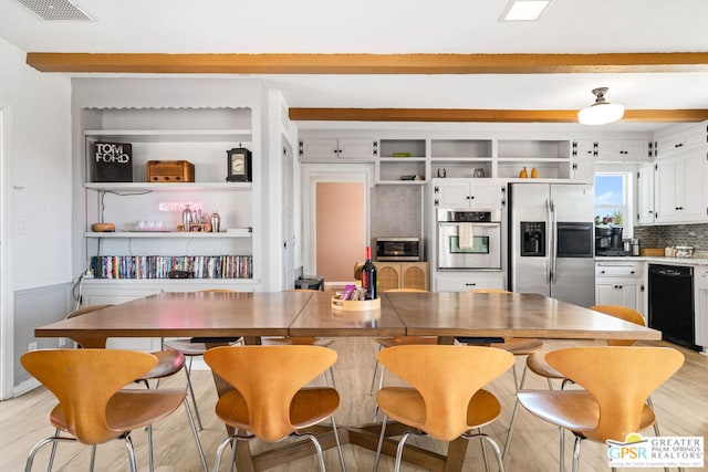 kitchen featuring a kitchen bar, backsplash, light hardwood / wood-style flooring, stainless steel appliances, and white cabinetry