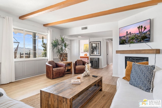 living room featuring beam ceiling and light hardwood / wood-style floors