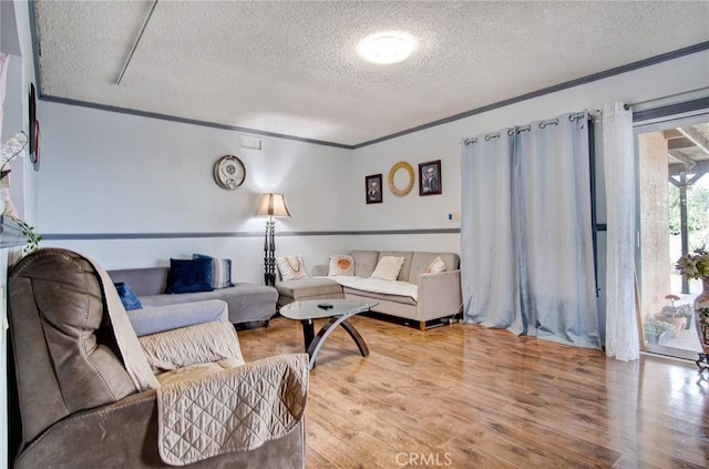 living room with crown molding, wood-type flooring, and a textured ceiling