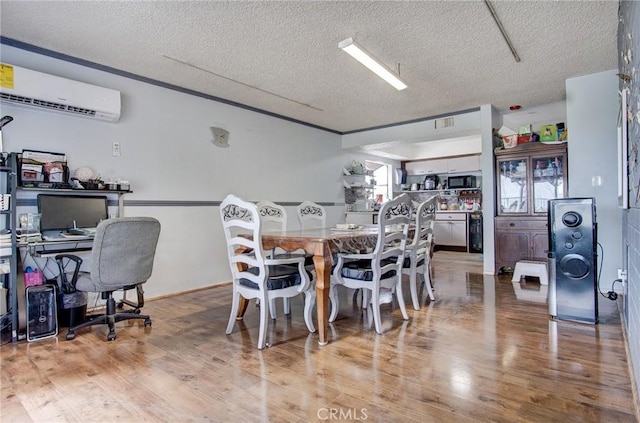 dining space featuring hardwood / wood-style floors, a wall mounted air conditioner, and a textured ceiling