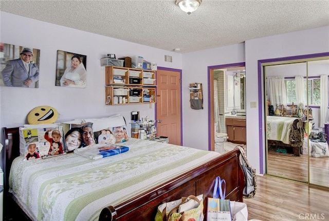 bedroom with connected bathroom, a closet, a textured ceiling, and light wood-type flooring