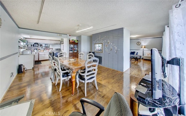 dining area with a textured ceiling and light hardwood / wood-style flooring