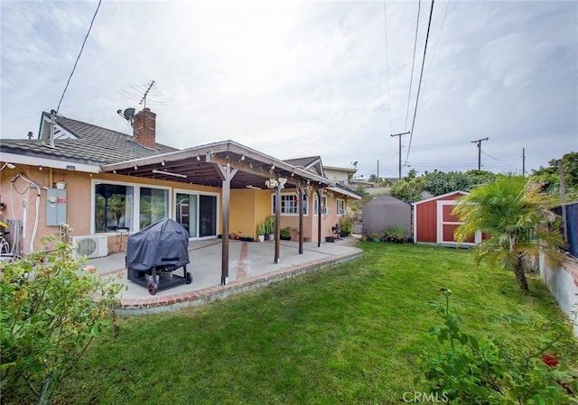 rear view of house with a storage unit, a yard, and a patio