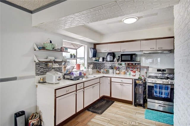 kitchen featuring white cabinets, tasteful backsplash, light hardwood / wood-style floors, and stainless steel gas range