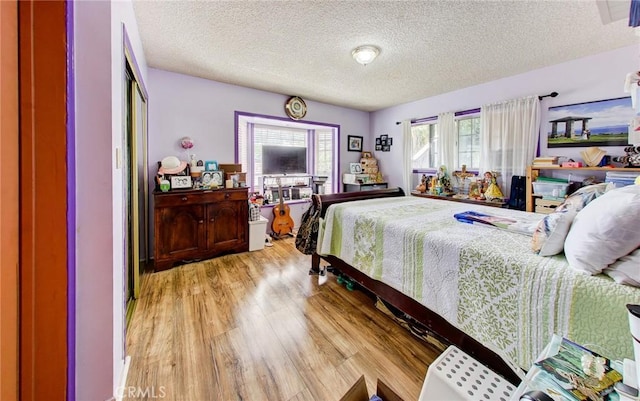 bedroom featuring a textured ceiling, light wood-type flooring, and multiple windows