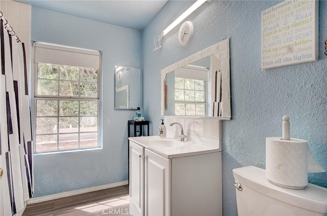 bathroom with vanity, hardwood / wood-style flooring, toilet, and a healthy amount of sunlight