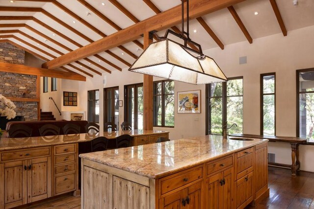 kitchen featuring dark hardwood / wood-style flooring, sink, a center island with sink, and beam ceiling