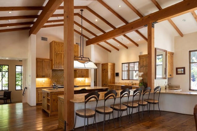 kitchen with decorative backsplash, a kitchen breakfast bar, high vaulted ceiling, and kitchen peninsula