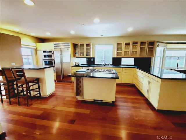 kitchen featuring a center island, stainless steel appliances, dark wood-type flooring, kitchen peninsula, and a breakfast bar