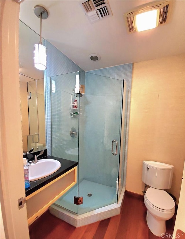 bathroom with hardwood / wood-style floors, vanity, toilet, and an enclosed shower