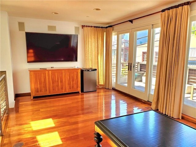 unfurnished living room with a wealth of natural light, french doors, and light wood-type flooring