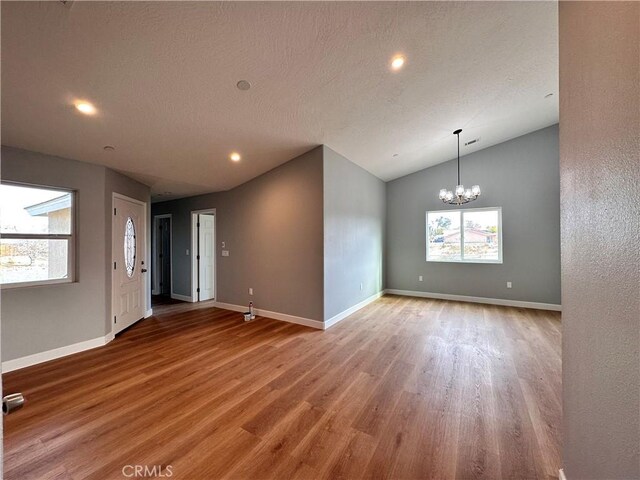 spare room featuring a chandelier, light hardwood / wood-style floors, and vaulted ceiling