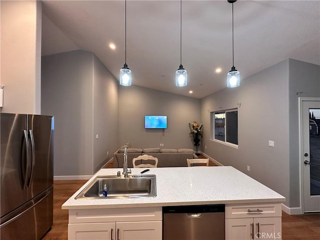 kitchen featuring appliances with stainless steel finishes, vaulted ceiling, a kitchen island with sink, sink, and white cabinets