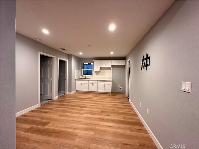 unfurnished living room with sink and light hardwood / wood-style floors