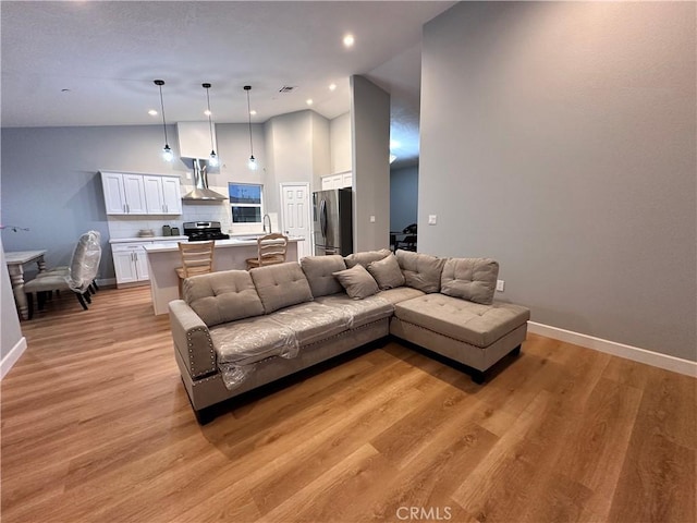 living room with lofted ceiling, sink, and light hardwood / wood-style flooring