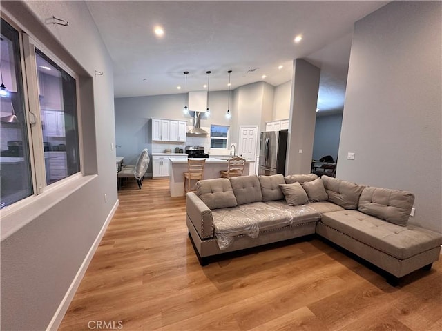 living room featuring sink, light hardwood / wood-style floors, and lofted ceiling