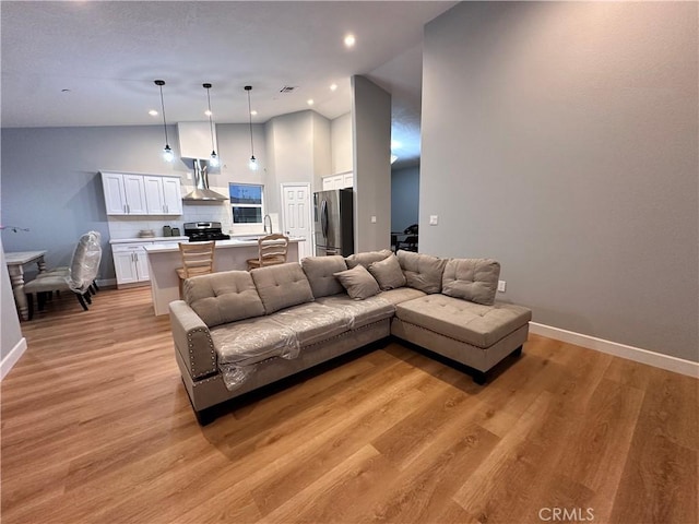 living room featuring vaulted ceiling, light hardwood / wood-style flooring, and sink