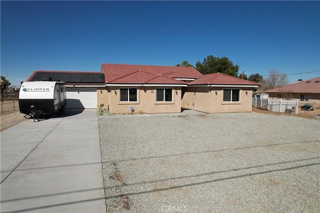 view of front facade with stucco siding, an attached garage, driveway, and fence